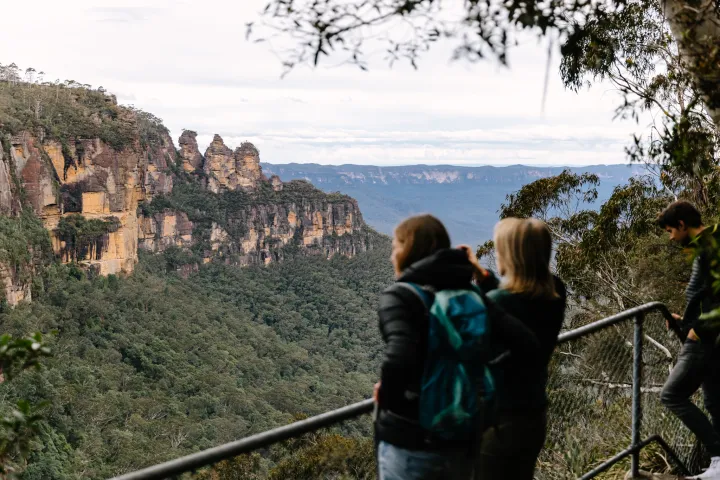 Tourists on a lookout observing a scenic mountain landscape with rock formations.