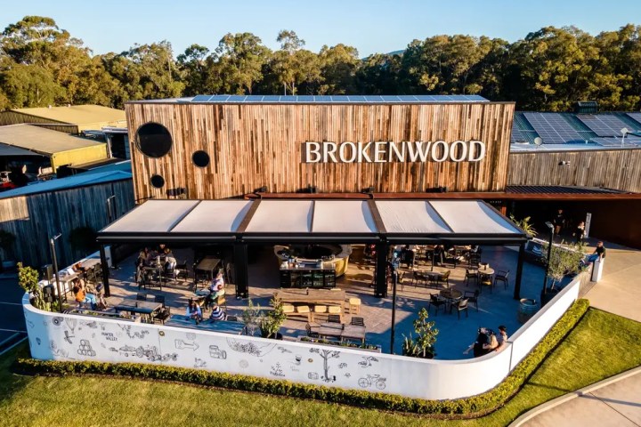Outdoor seating area of Brokenwood winery with wooden facade and trees in the background.