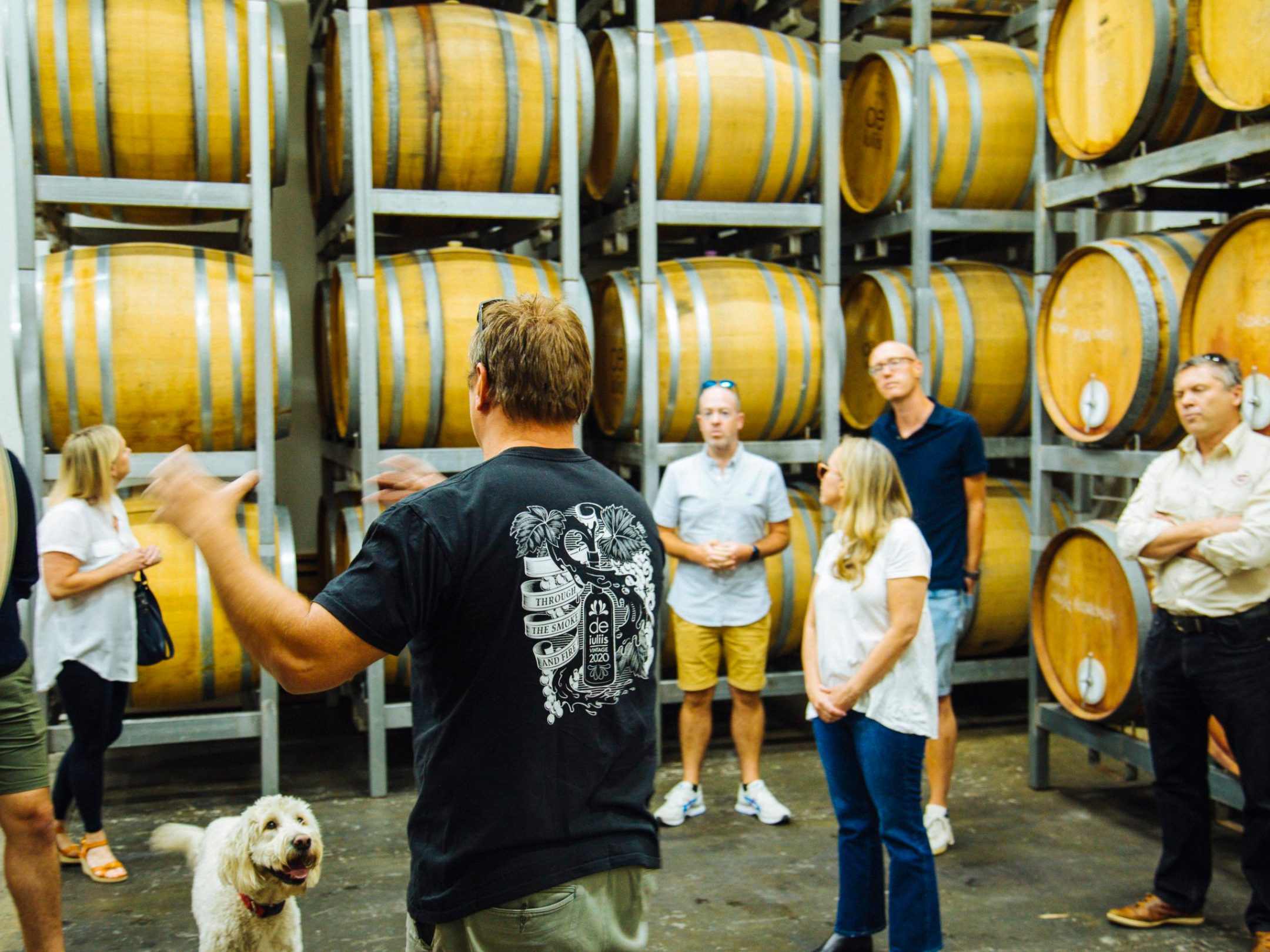 Man speaking to group in room of wine barrels