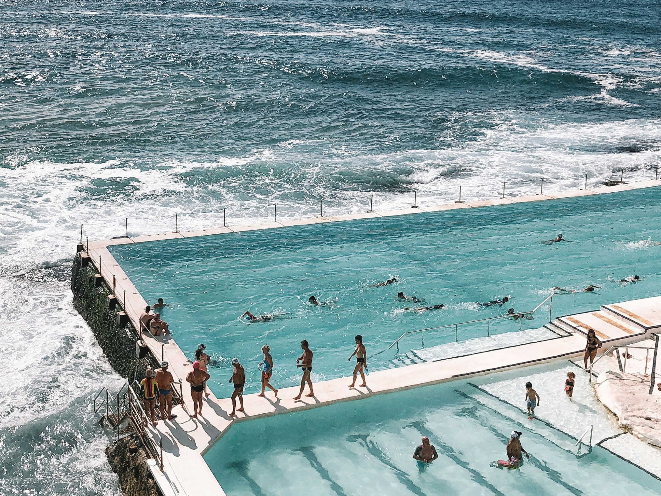 a group of people on a beach next to the ocean with Bondi Beach in the background