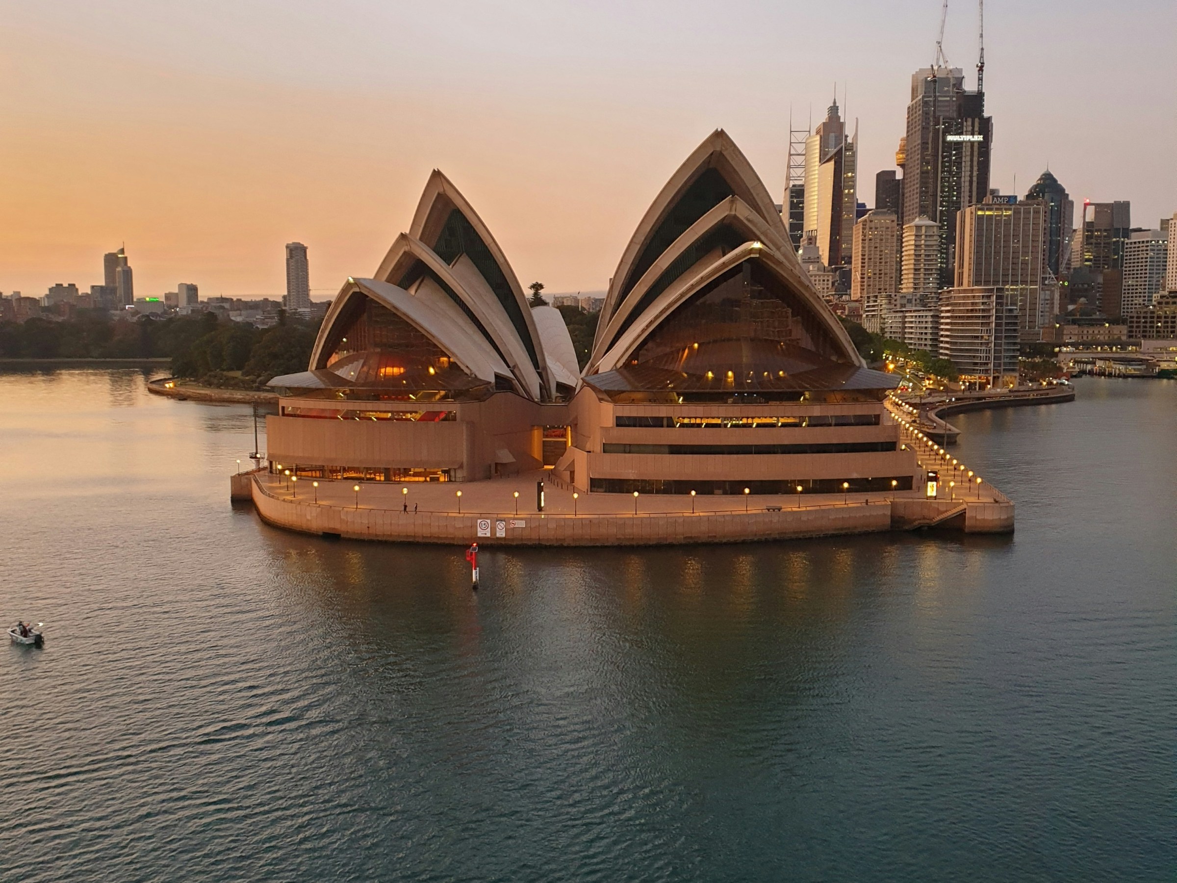 a small boat in a large body of water with Sydney Opera House in the background